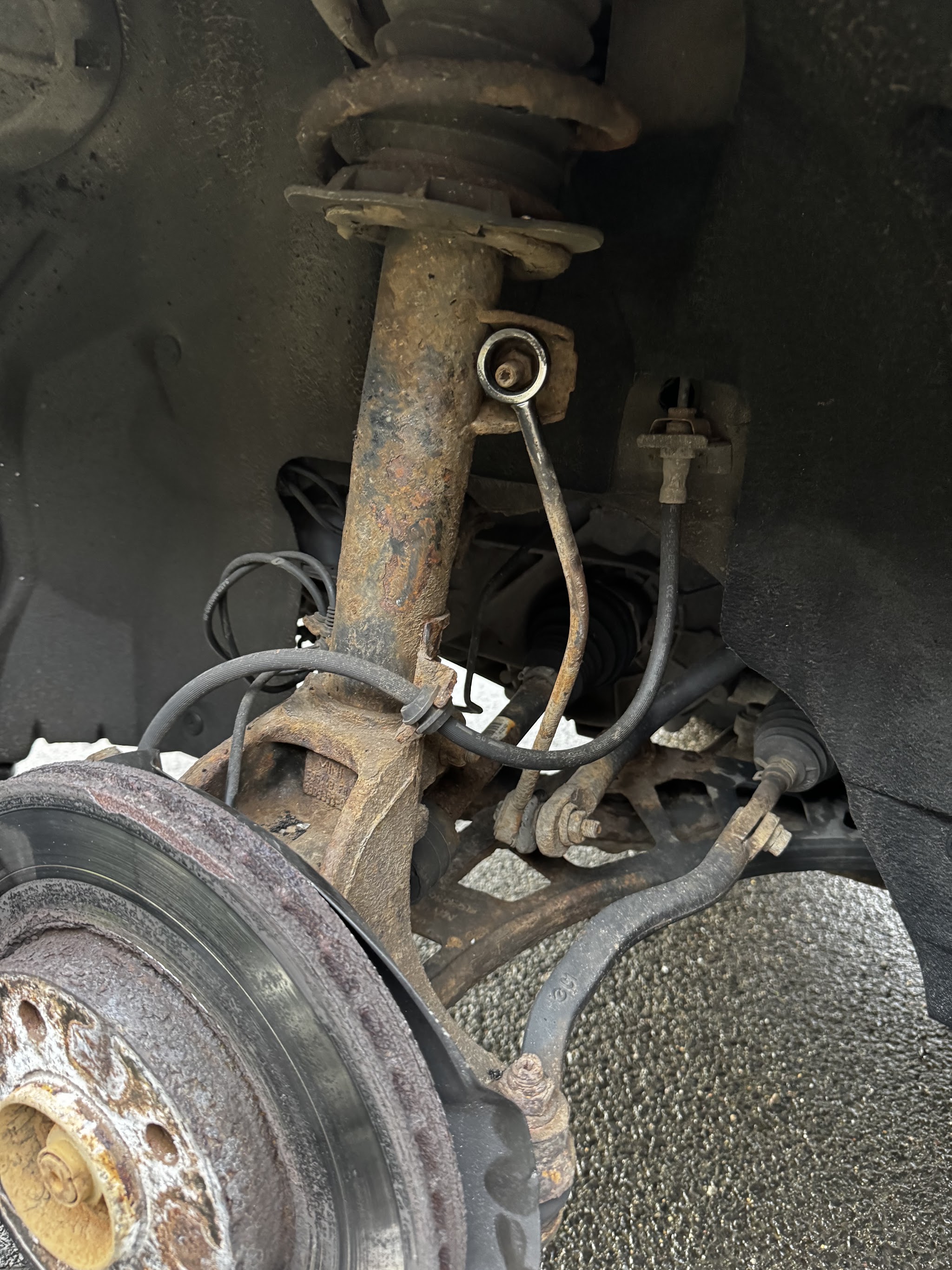 Under the wheel arch of a car with the wheel removed, showing the strut and a detached drop link